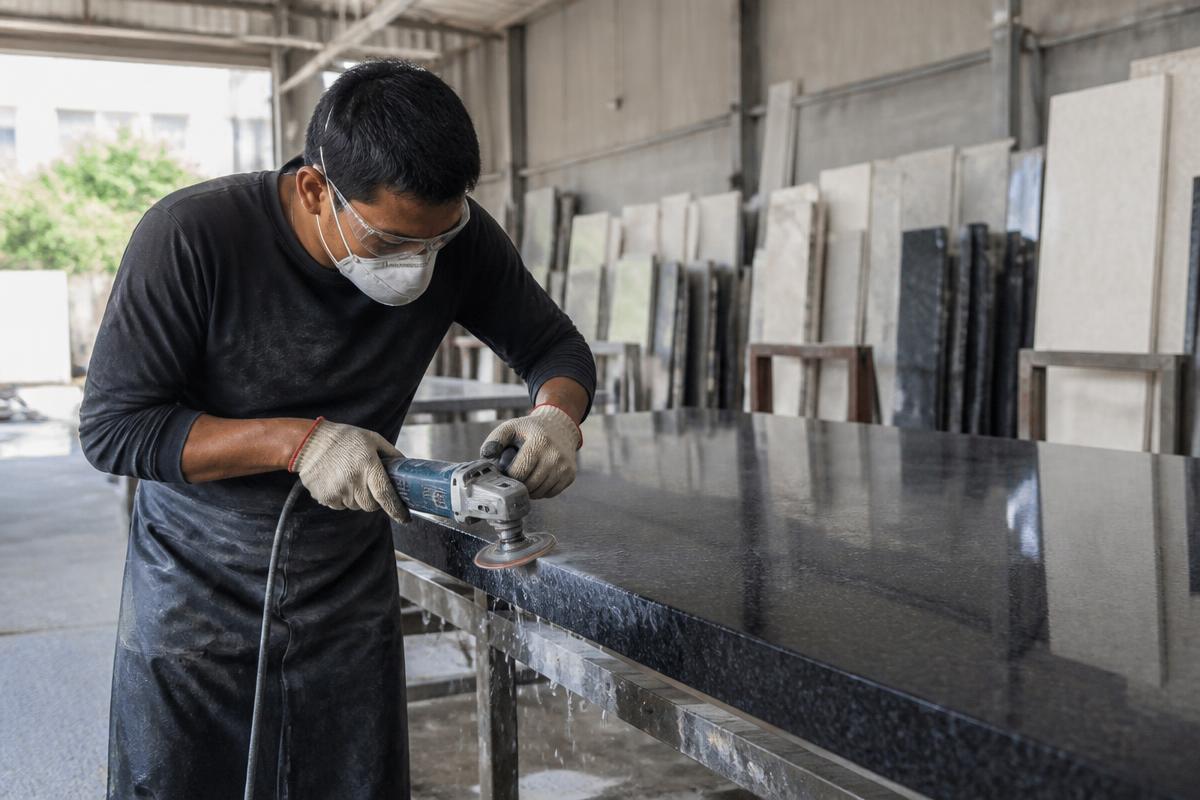 Thợ đá mài bóng cạnh tấm đá granite tại xưởng